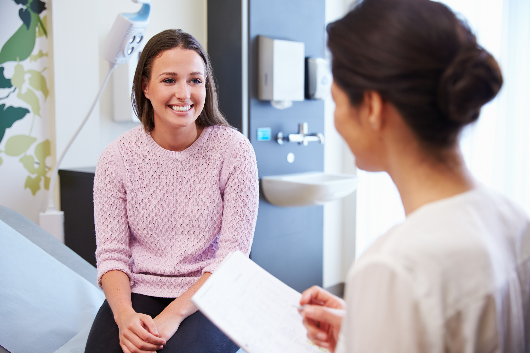 Female patient speaking with clinician before Pap smear screening in exam room